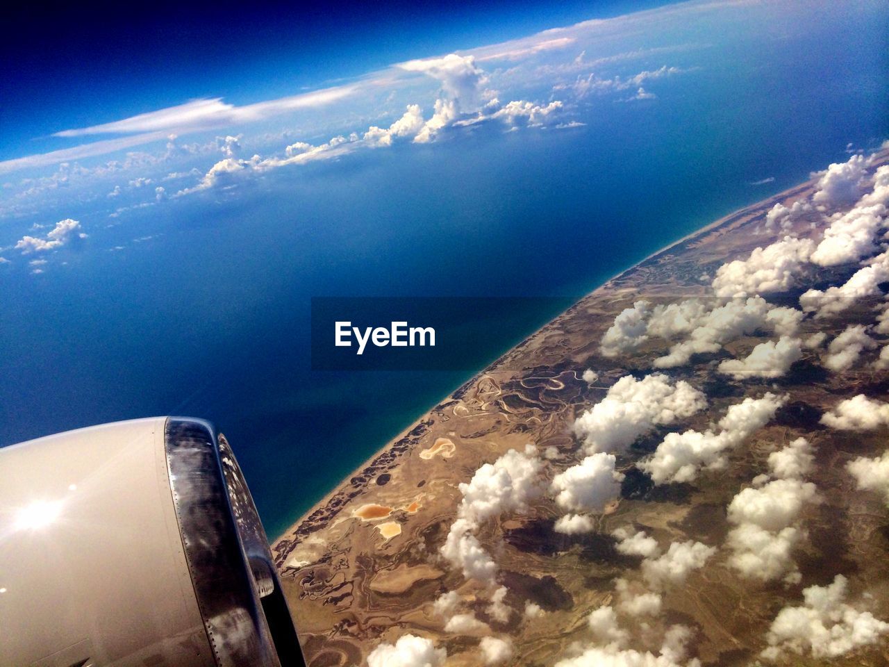 Cropped image of jet engine over landscape and ocean