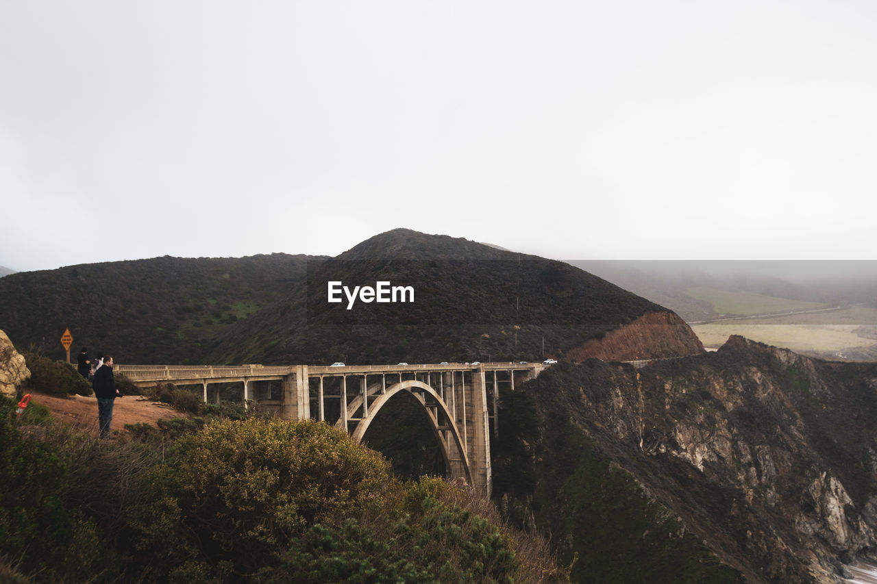 BRIDGE OVER MOUNTAINS AGAINST SKY