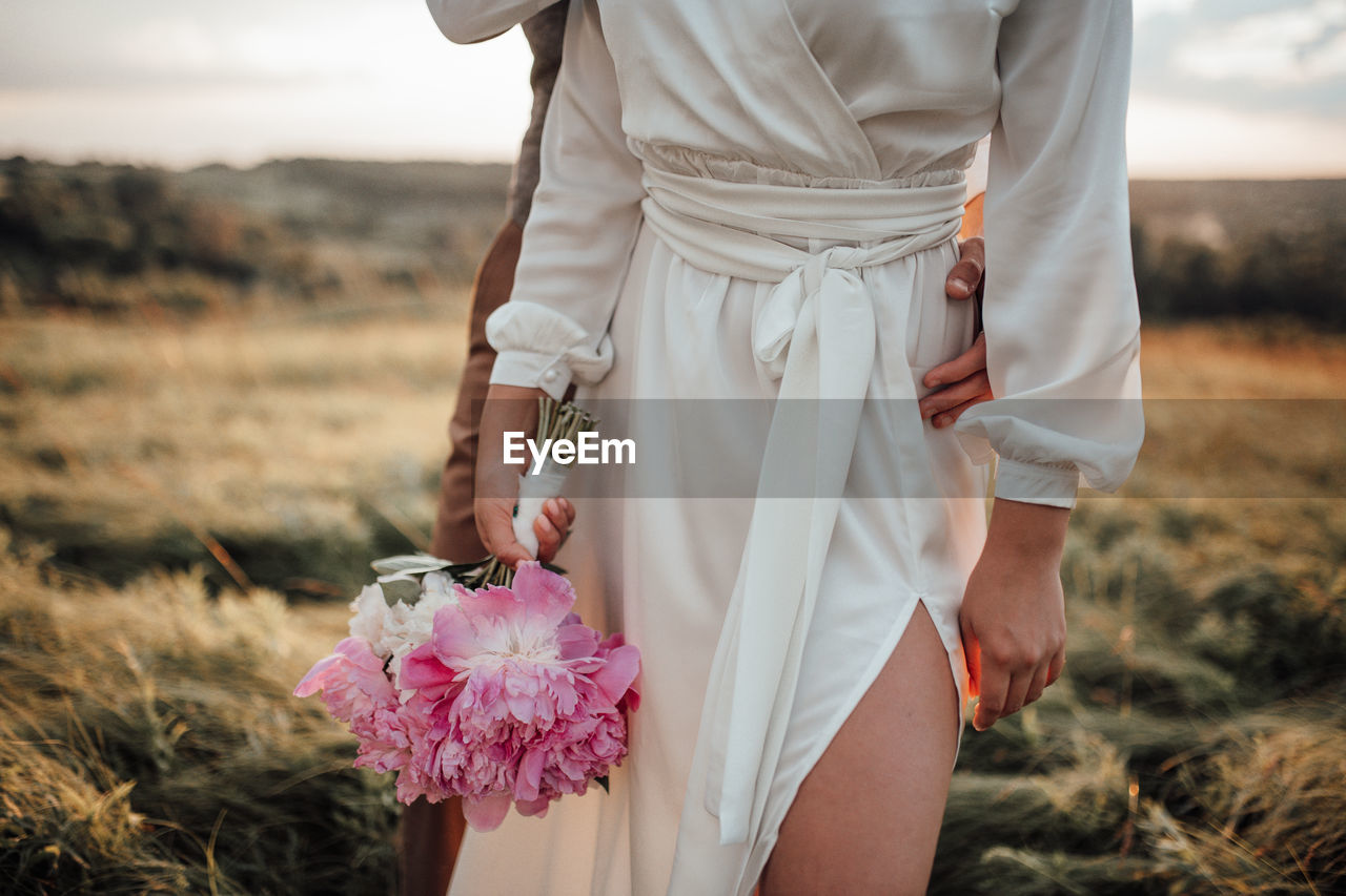 MIDSECTION OF WOMAN HOLDING WHITE FLOWER