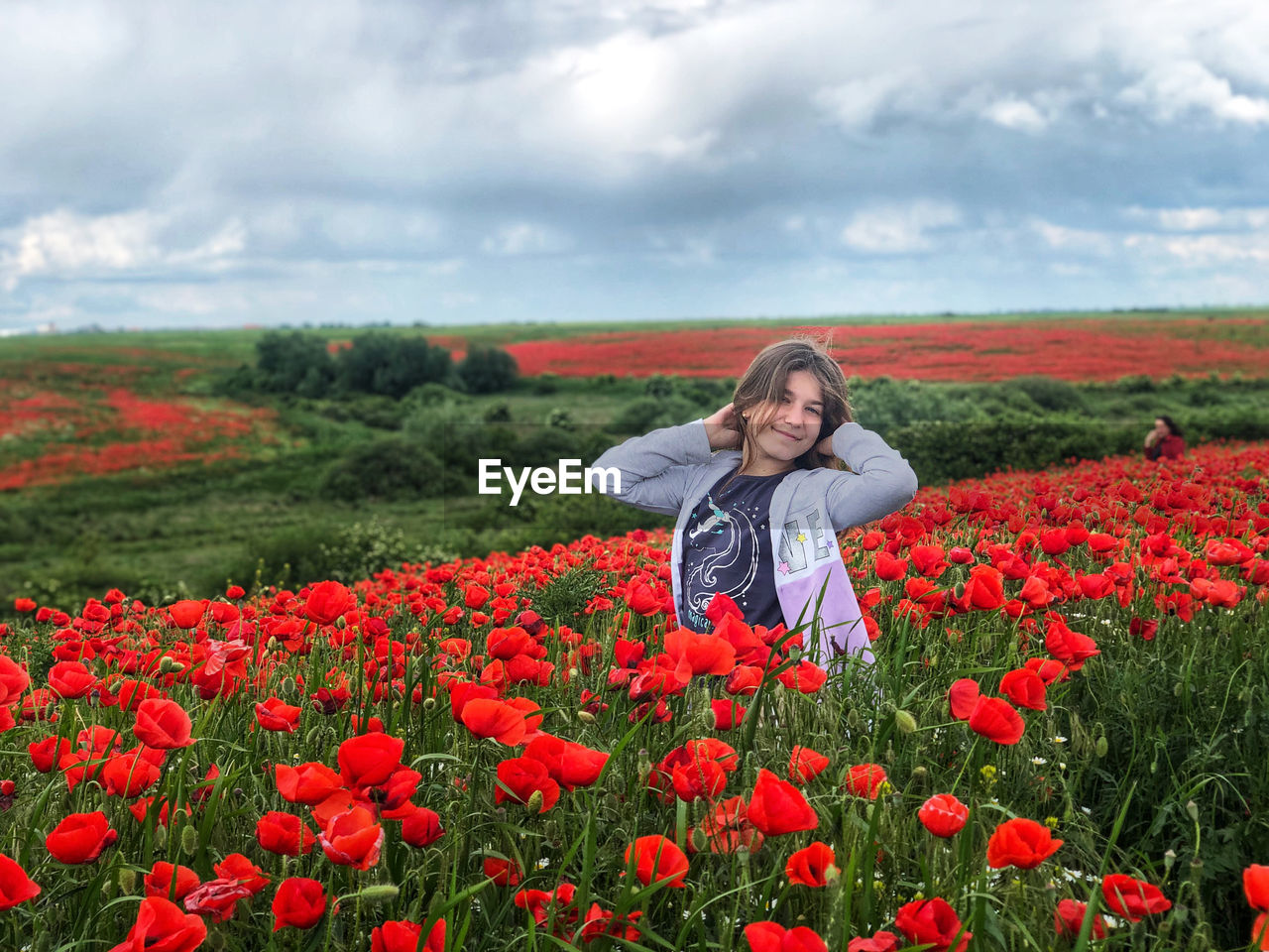 Portrait of young woman with red poppy flowers in field