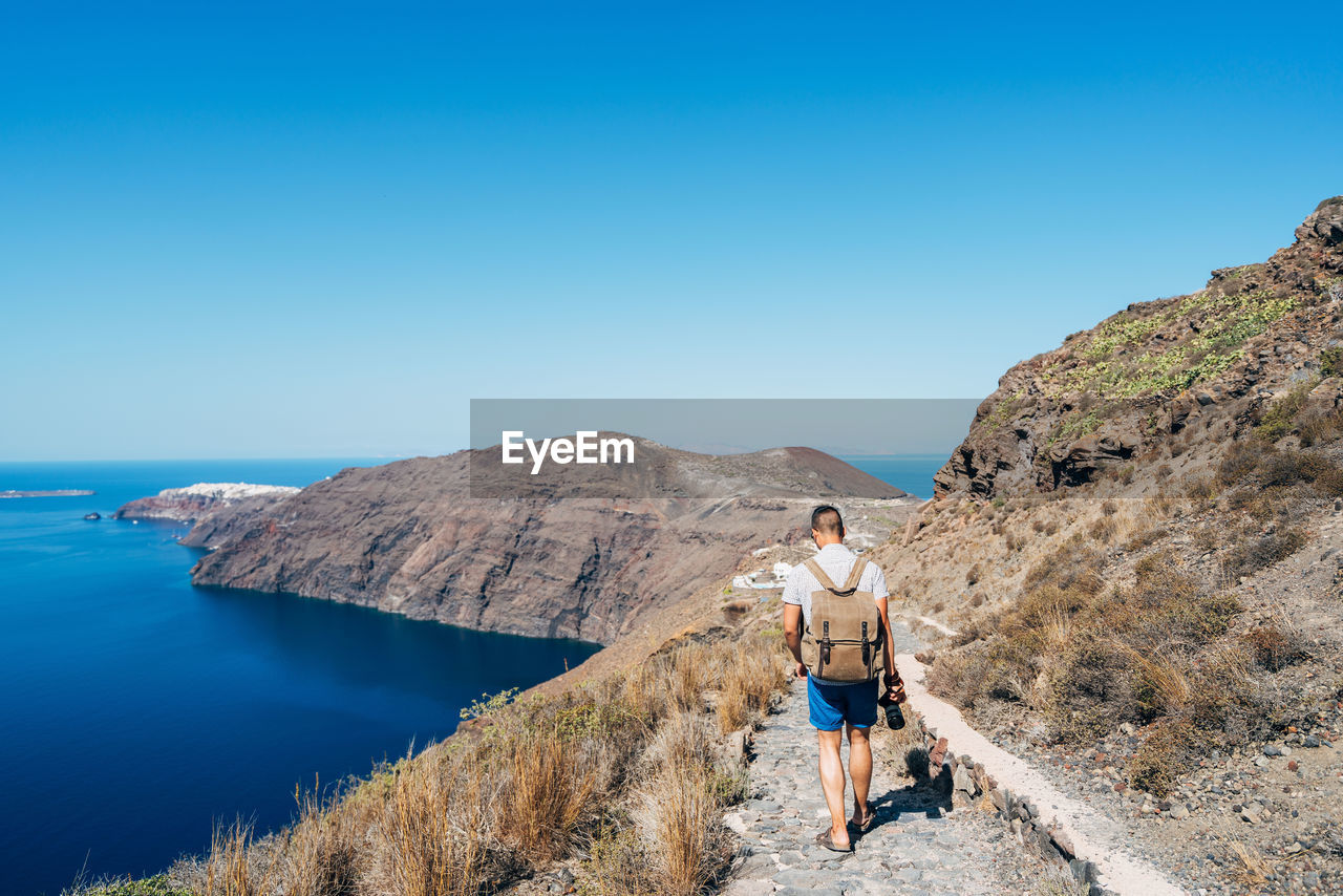 Full length of man on path against clear blue sky