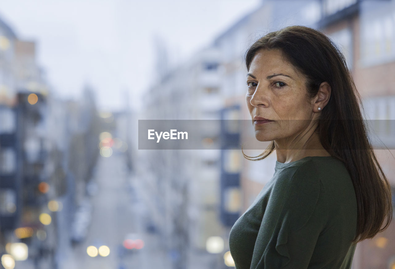 Portrait of mature woman standing next to window