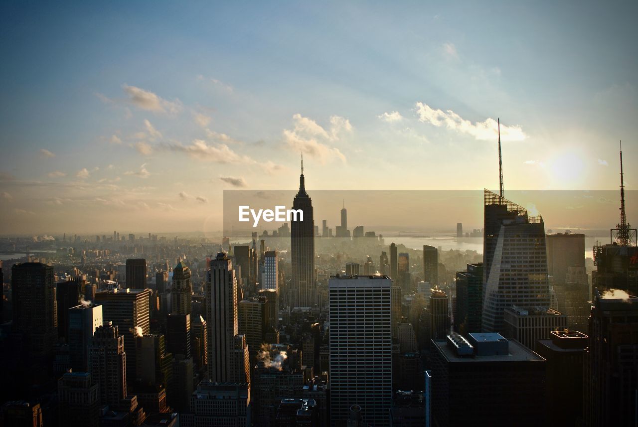 Empire state building in city against sky during sunset