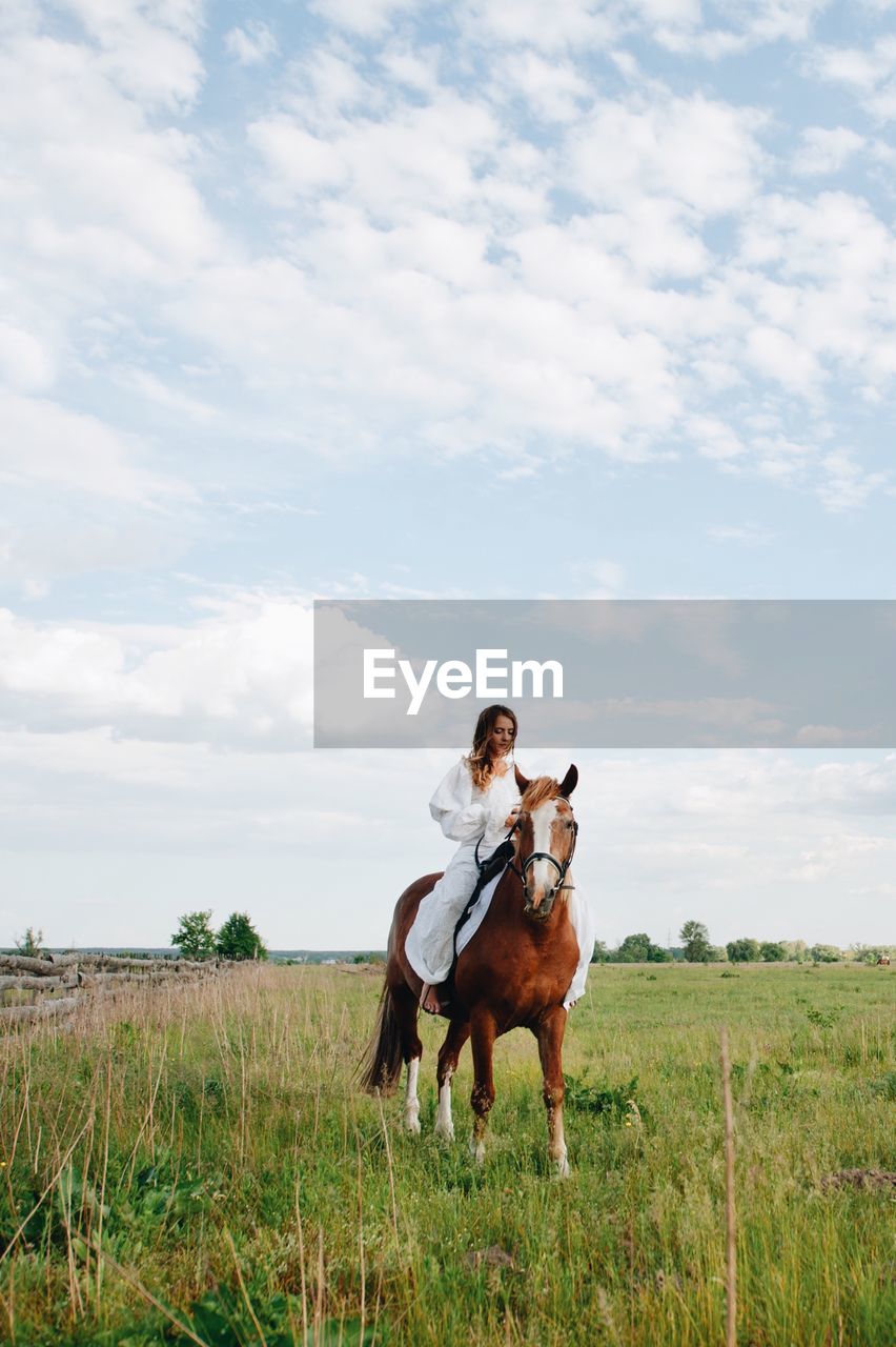 Young woman riding horse on field