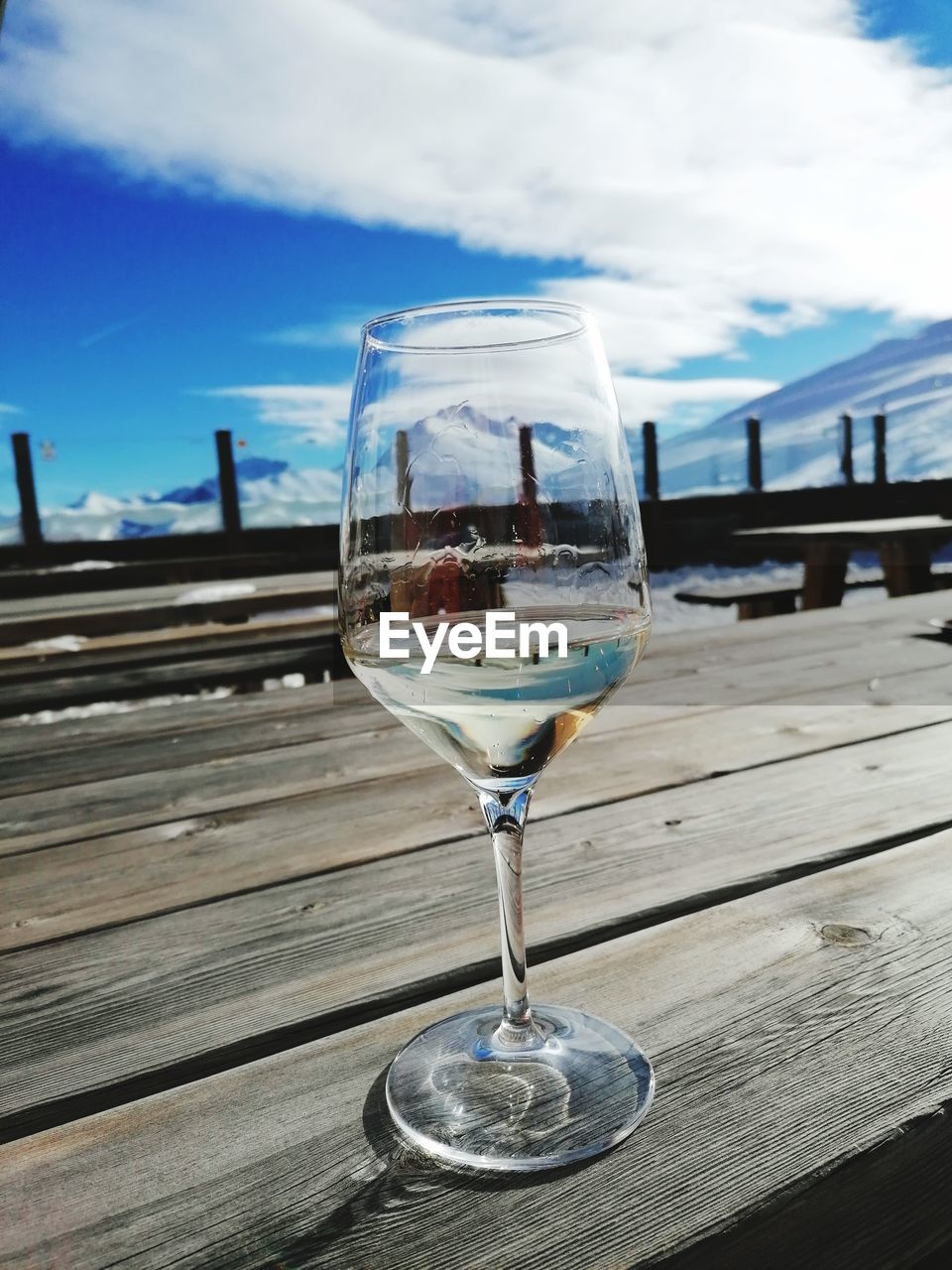 blue, refreshment, sky, glass, drink, cloud, food and drink, alcohol, wine, wood, wine glass, reflection, nature, day, table, drinking glass, no people, stemware, household equipment, outdoors, alcoholic beverage, water, freshness, sunlight, drinkware, food, transparent, close-up, railing, absence