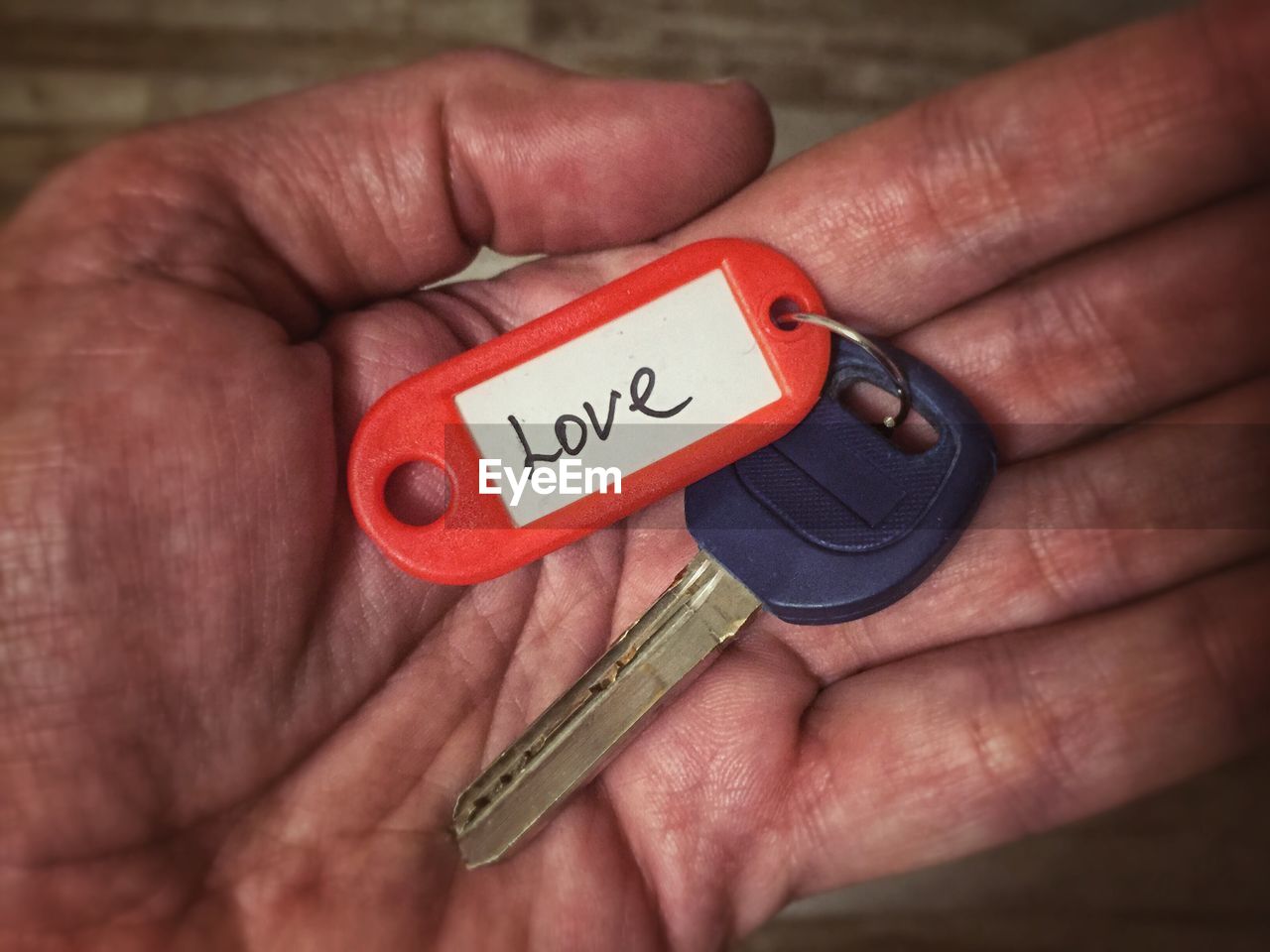 Cropped hand with key ring with love text