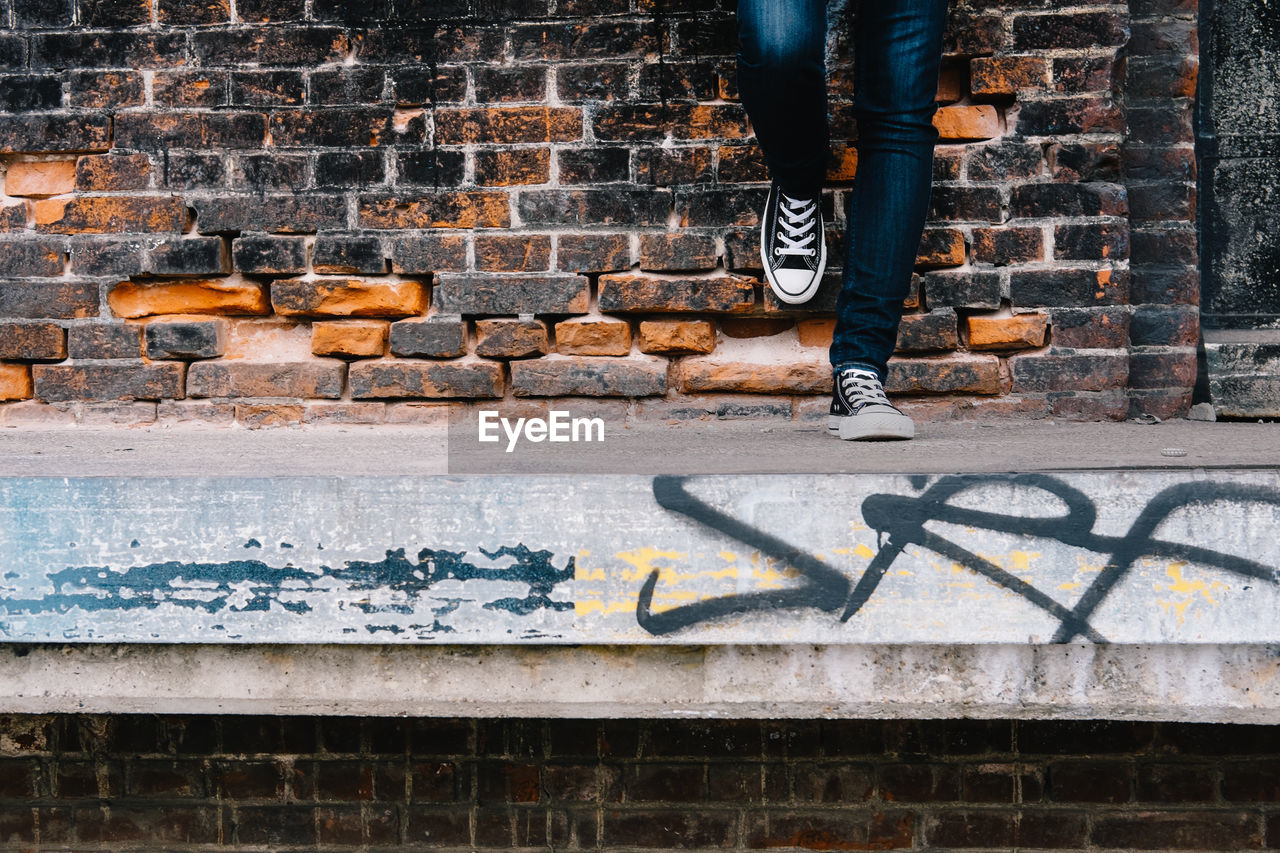 Low section of man standing by brick wall