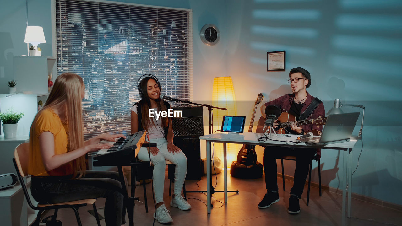 portrait of smiling friends using digital tablet while sitting on stage