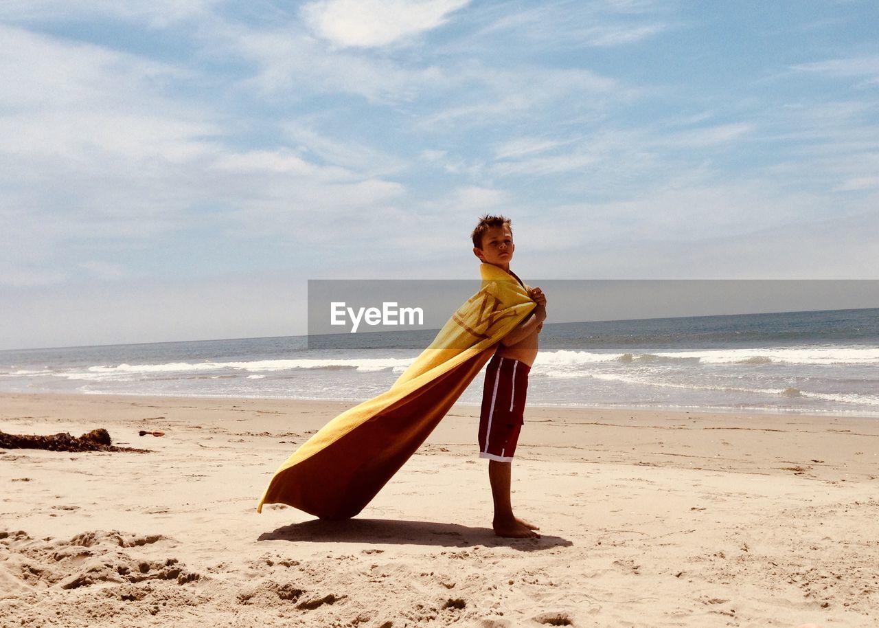 Boy with towel as a cape on beach