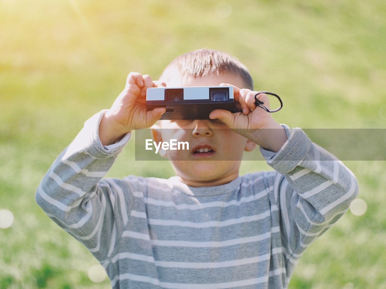 Boy looking through binoculars on grass