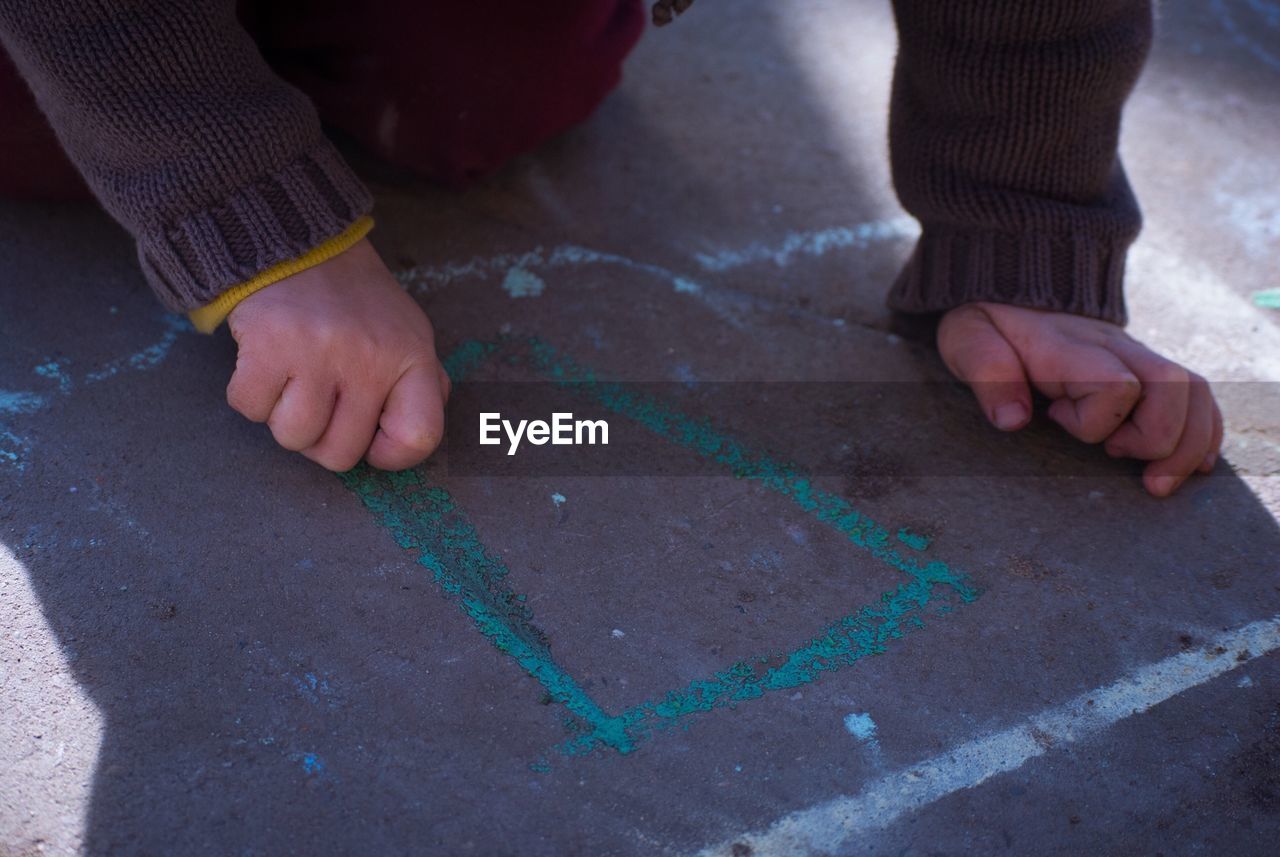 Cropped image of child writing with chalk on surface