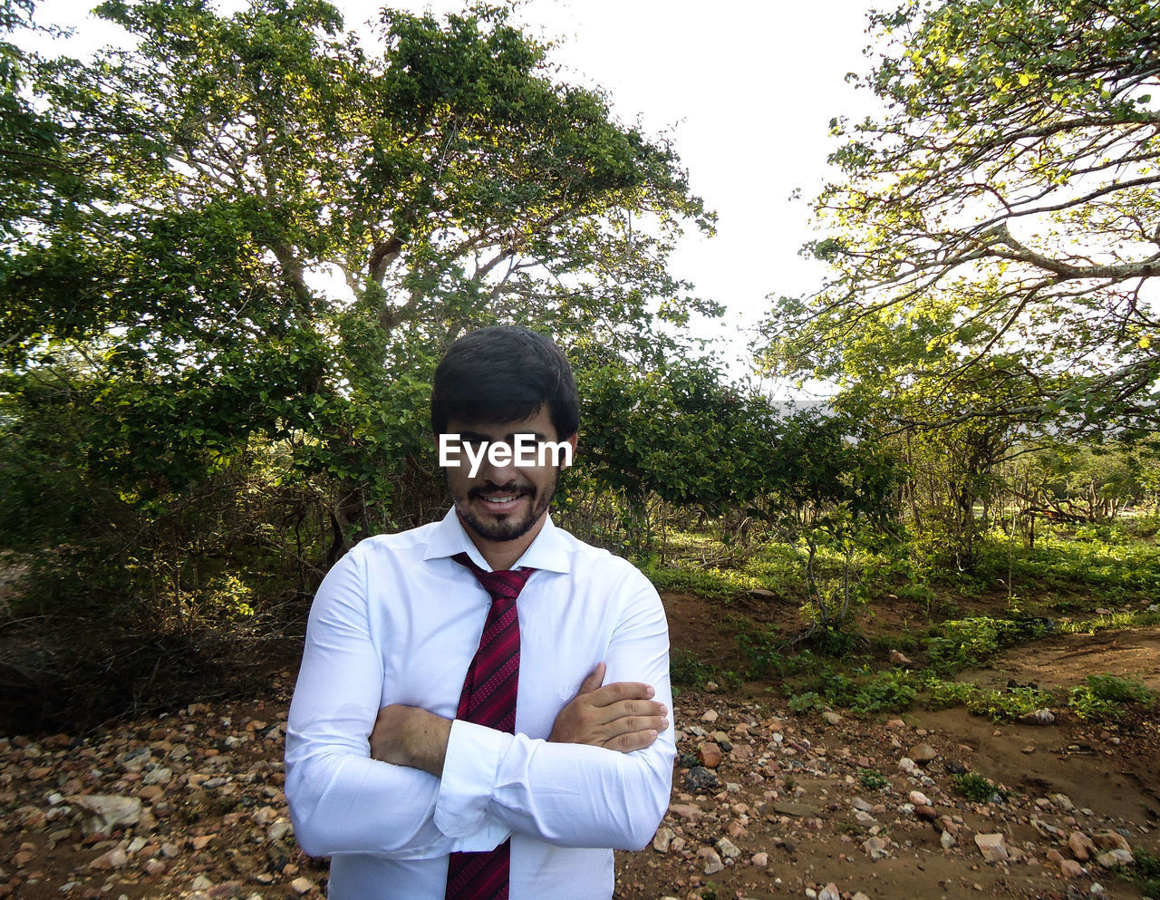 PORTRAIT OF YOUNG MAN STANDING BY TREES