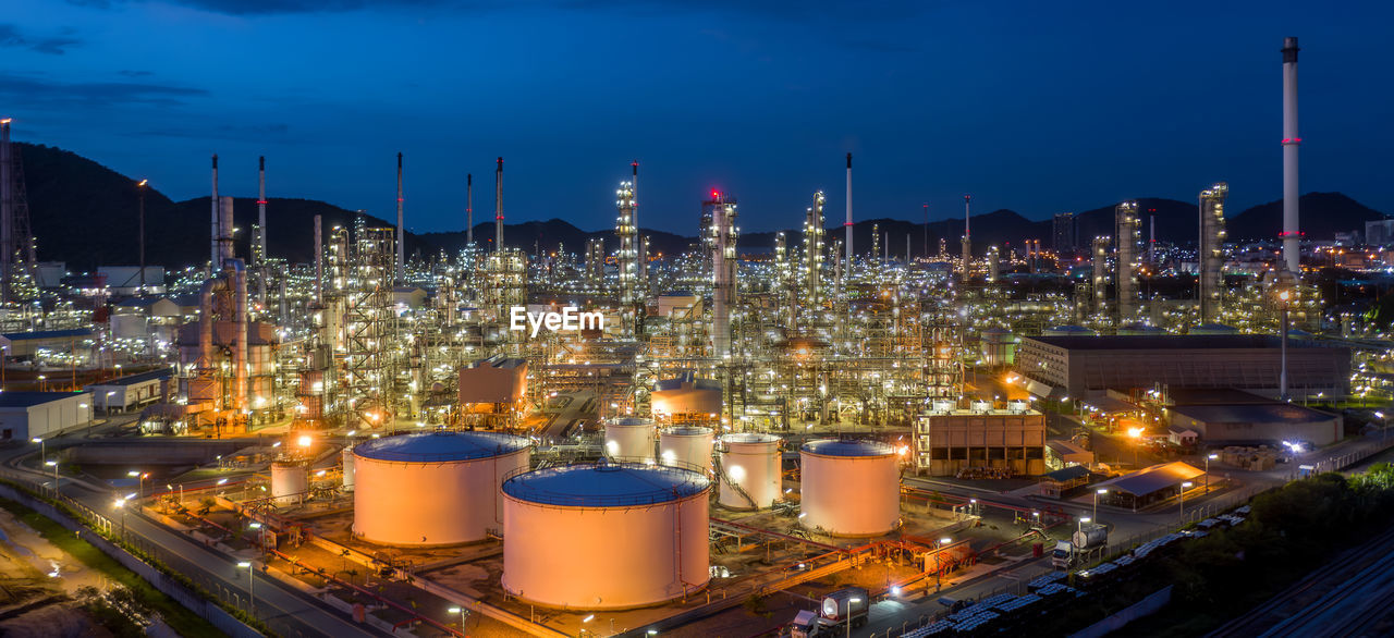 Aerial view oil and gas tank with oil refinery background at night, glitter lighting petrochemical.