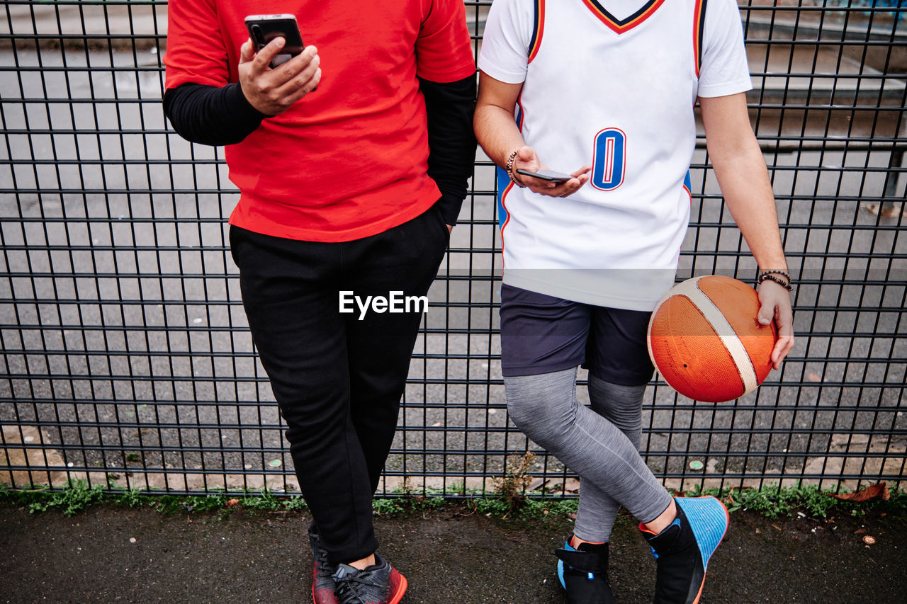 Cropped portrait of male friends checking their phone after a game at a basketball court. copy space.