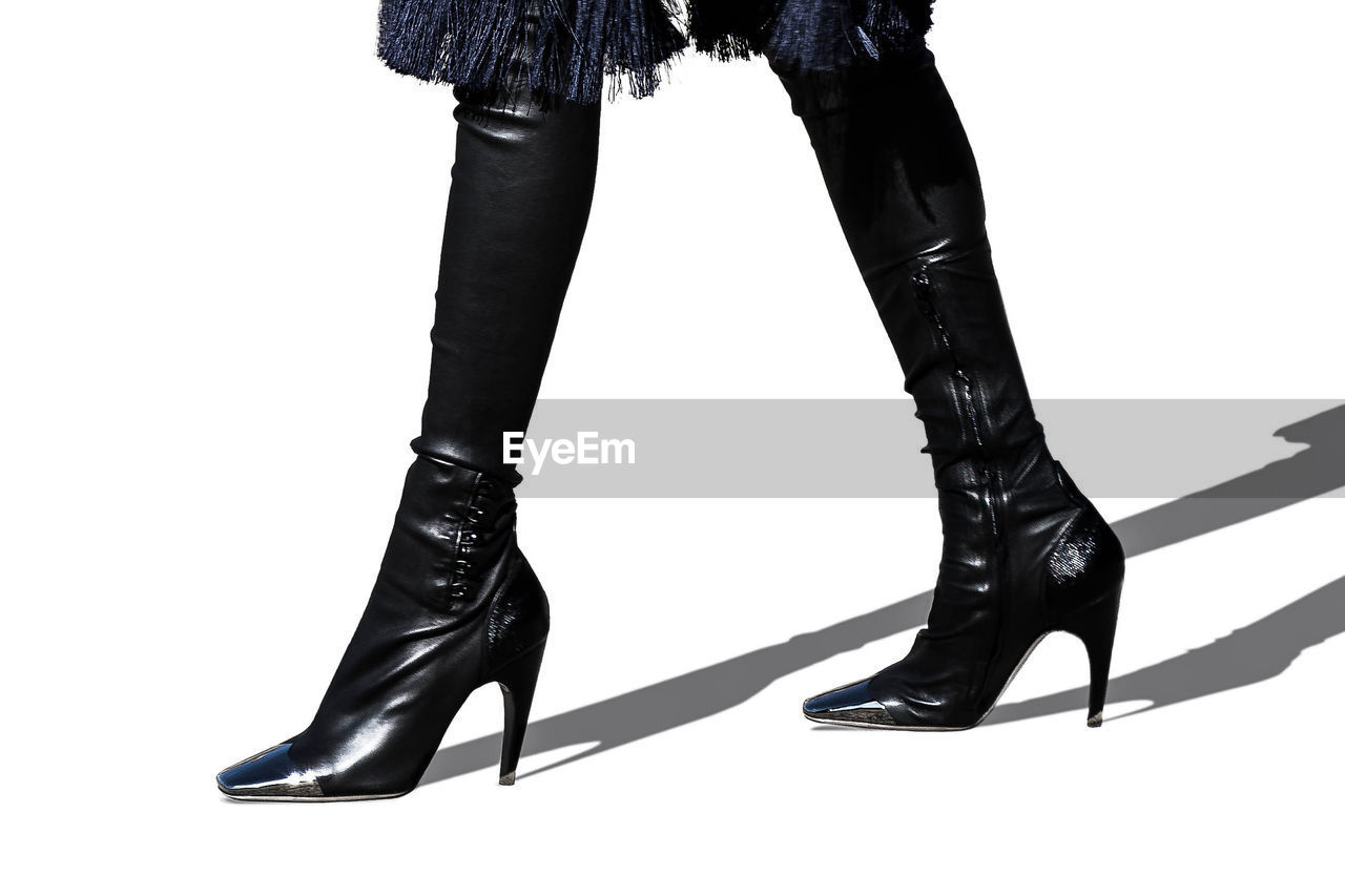 Low section of woman wearing high heels over white background