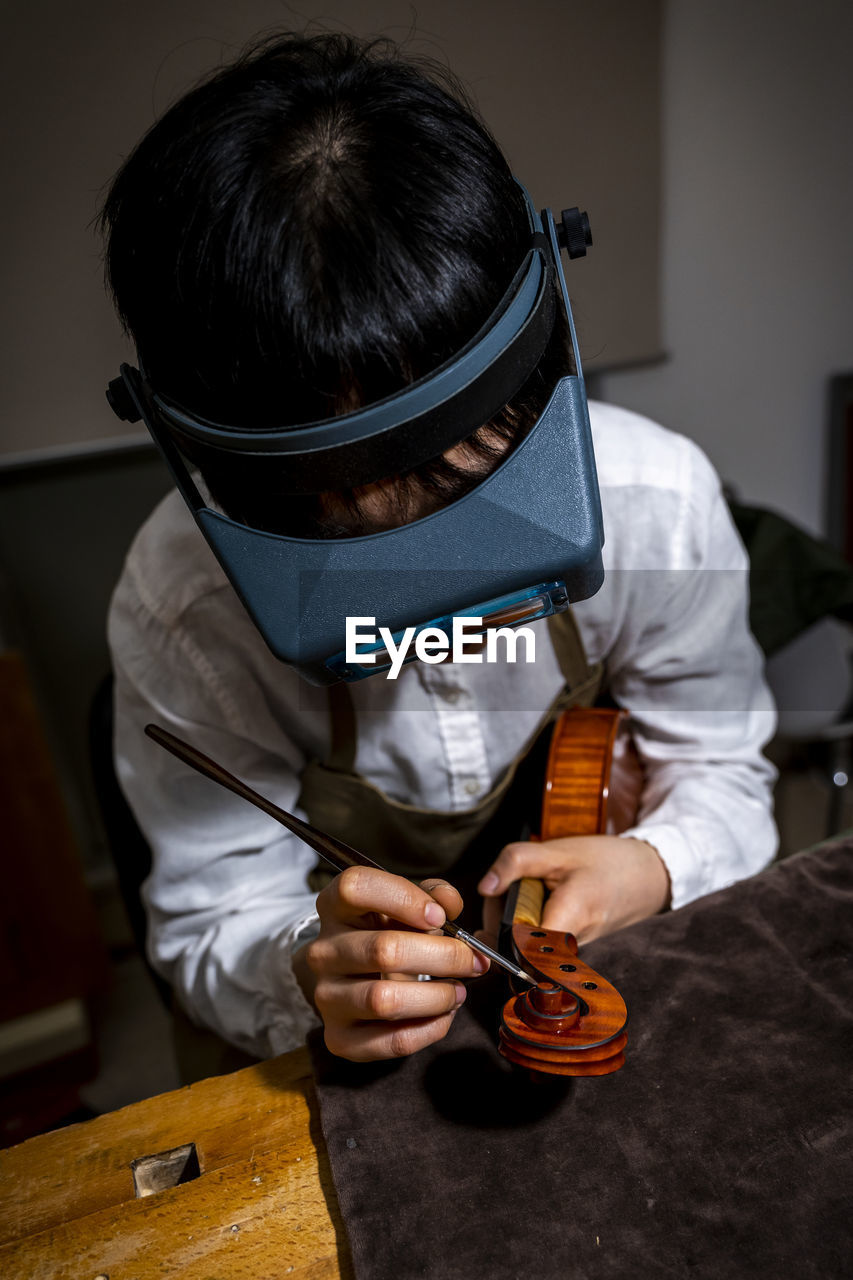 Young chinese violin maker at work in her workshop