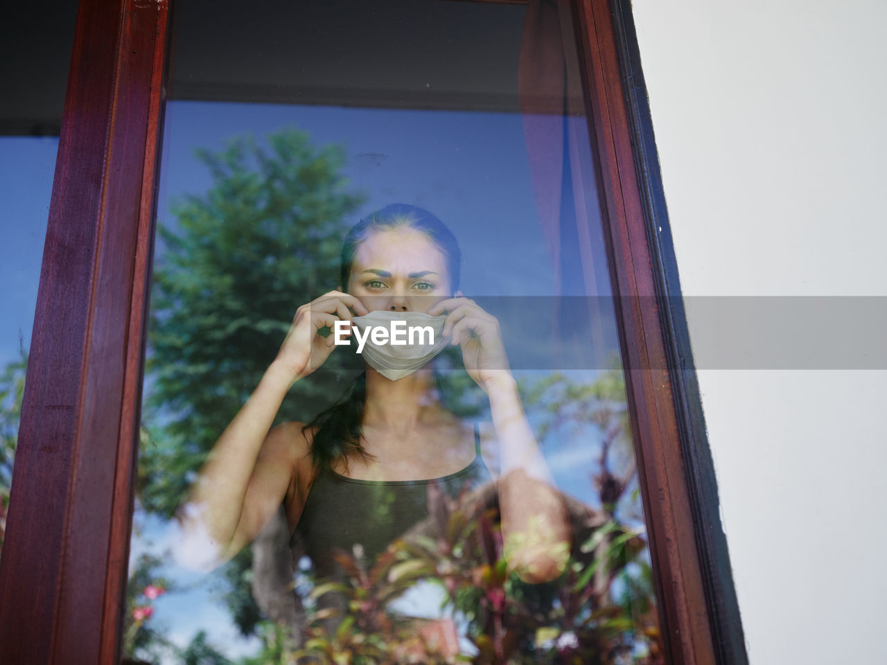 Portrait of young woman drinking glass window