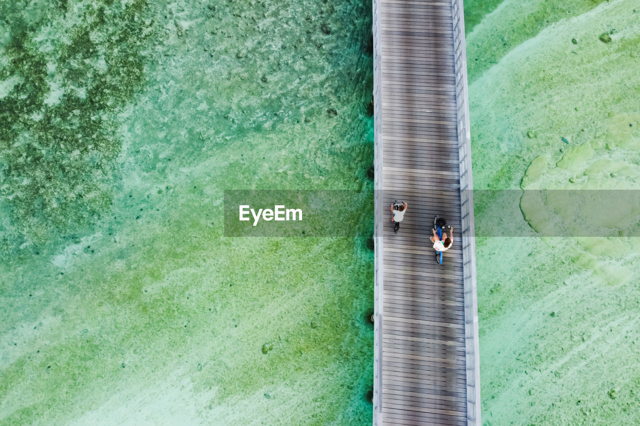 Woman and kid riging their bikes over the ocean. aerial view