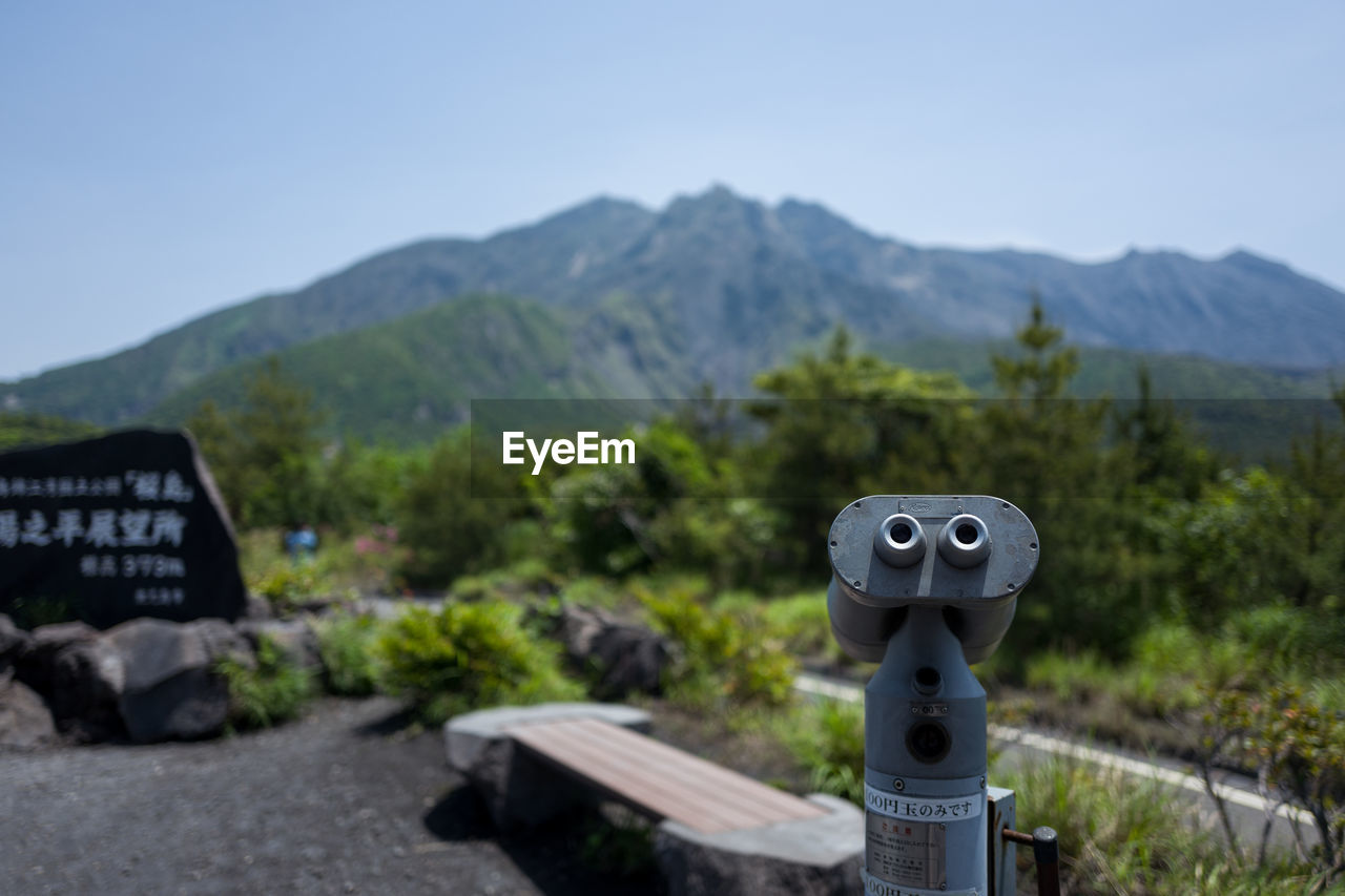 CLOSE-UP OF COIN-OPERATED BINOCULARS AGAINST MOUNTAIN