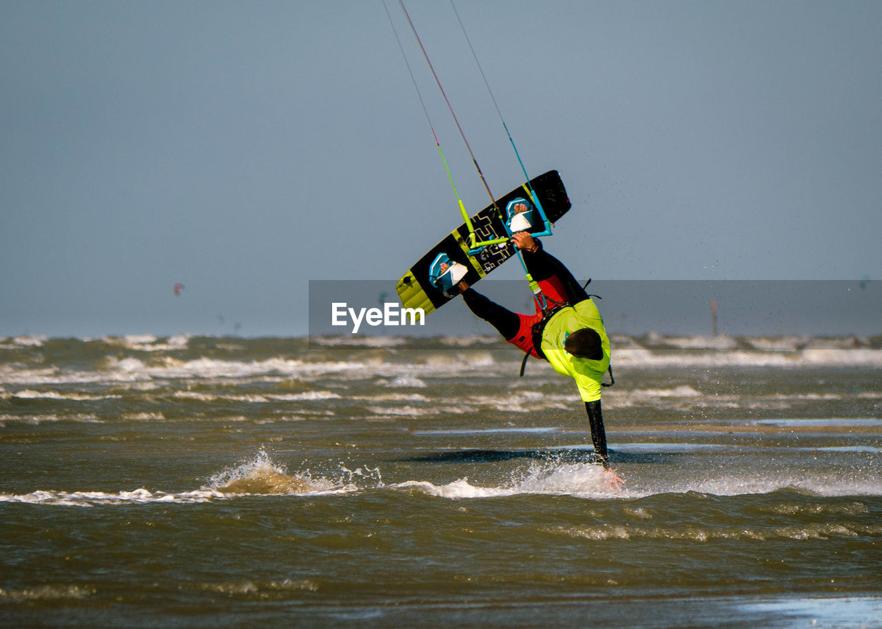 Kite surfer touches water with hand while being upside-down