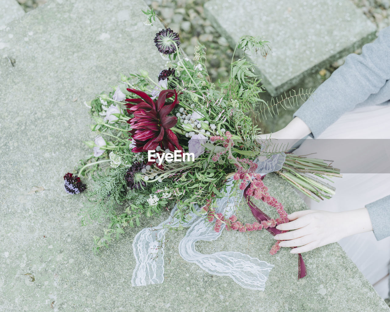 Cropped image of bridesmaid holding flower bouquet over retaining wall