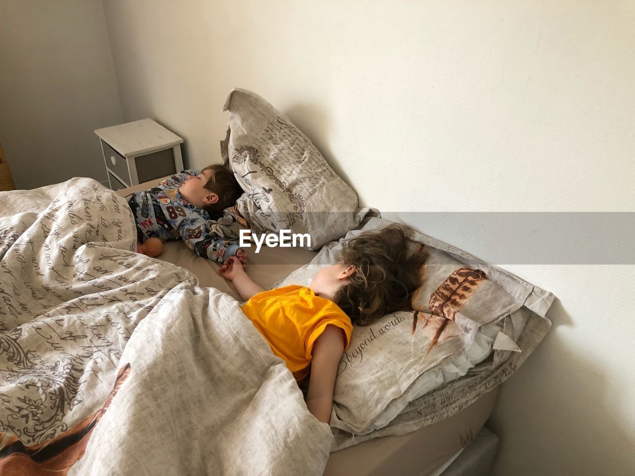 Cute siblings sleeping on bed at home