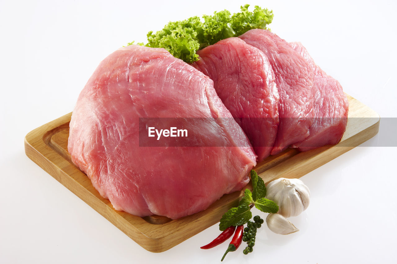 Close-up of raw meat on cutting board over white background