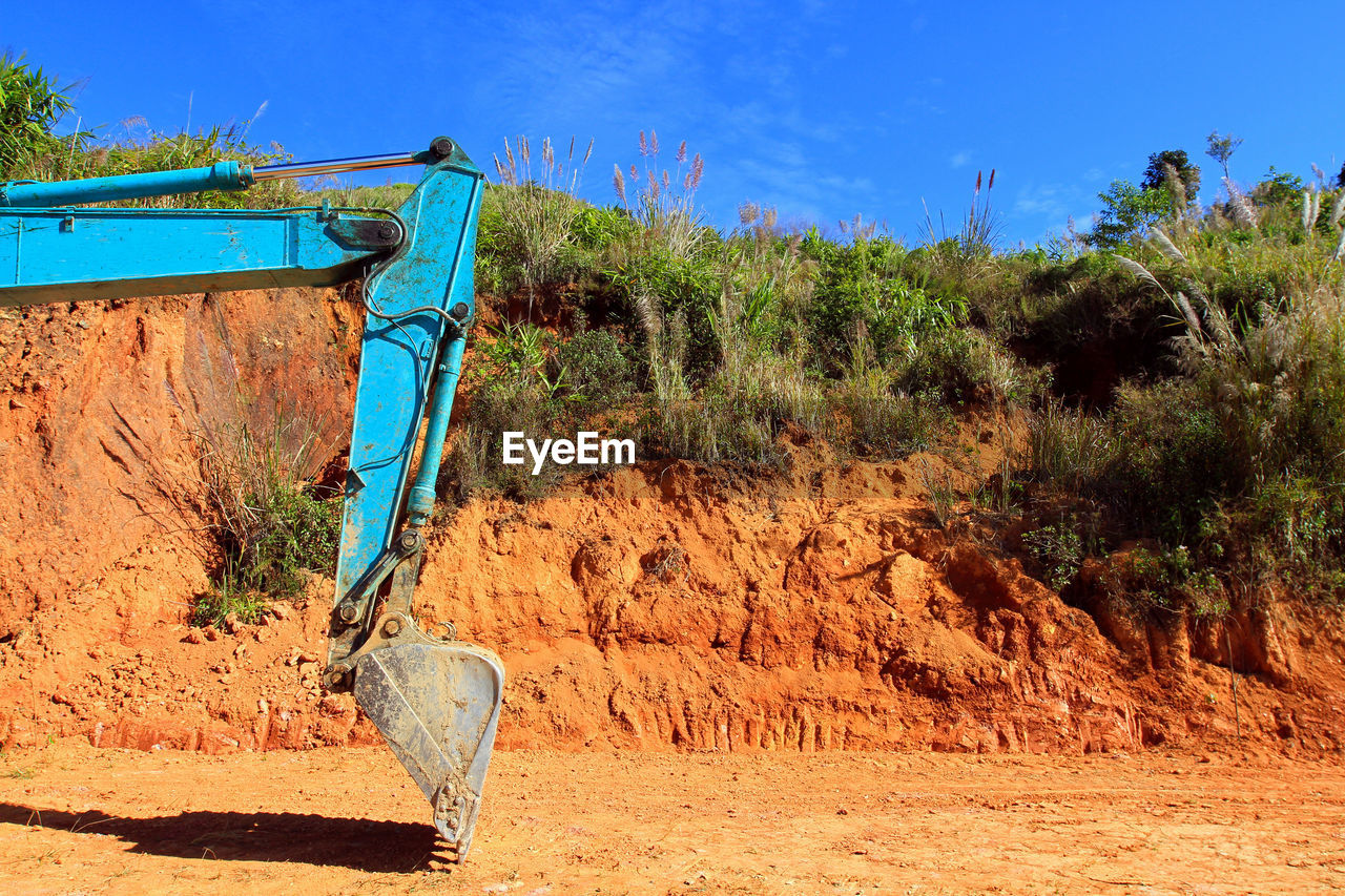 Earth mover on field against blue sky