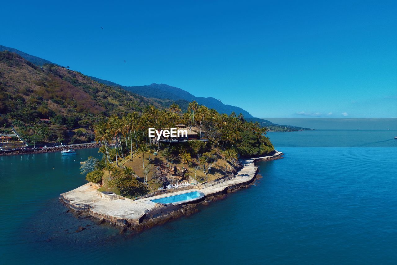 Scenic view of sea by building against blue sky