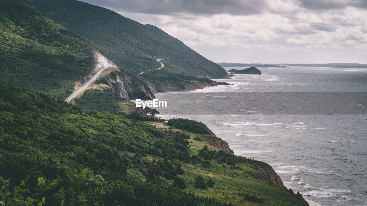 Scenic view of sea by mountains against sky