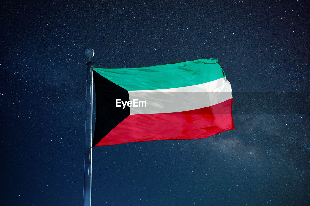 Low angle view of kuwaiti flag against star field sky