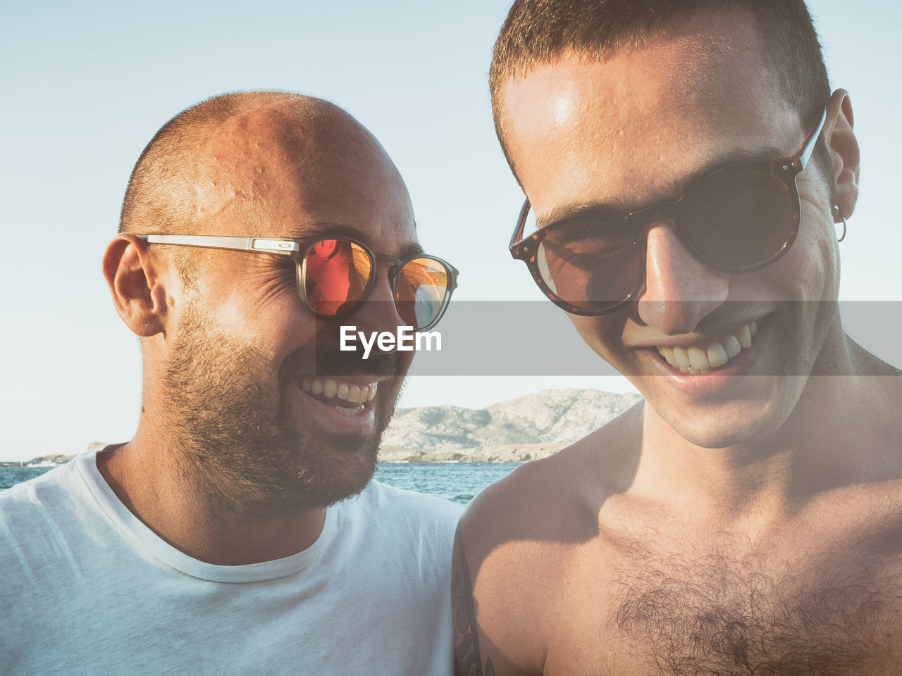 Close-up of smiling friends wearing sunglasses at beach
