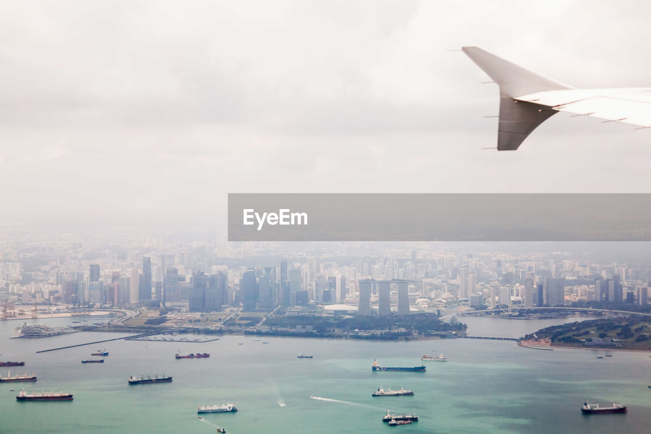 AERIAL VIEW OF SEA BY BUILDINGS AGAINST SKY