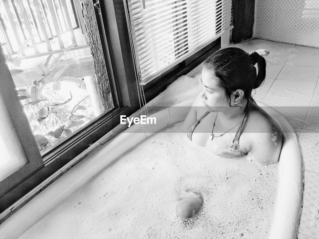 Thoughtful young woman in bathtub at home