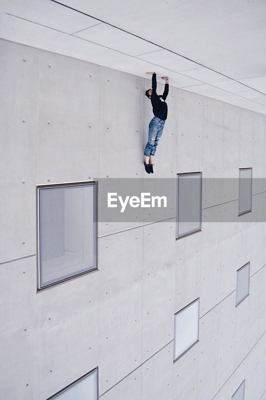 FULL LENGTH OF MAN WITH ARMS RAISED ON WALL