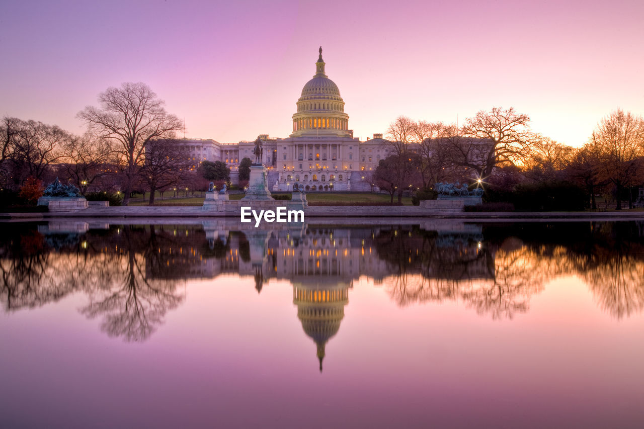 Reflection of illuminated building in river at sunset