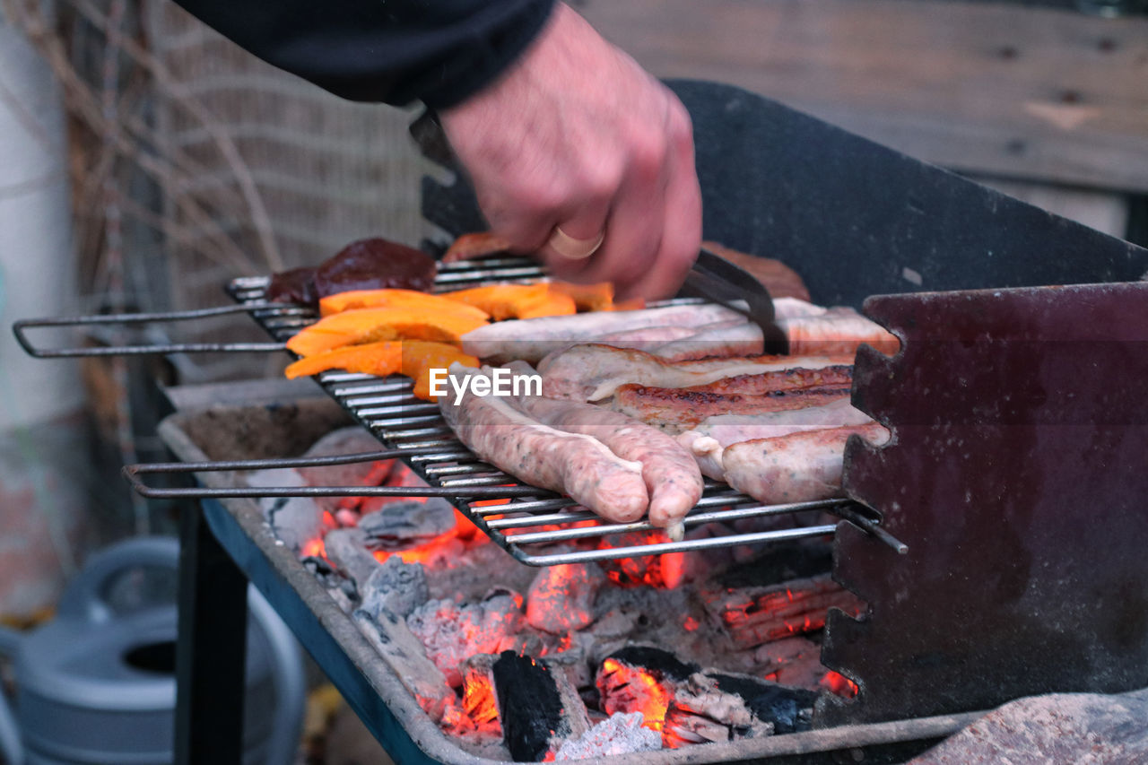 Midsection of man preparing meat on barbecue grill