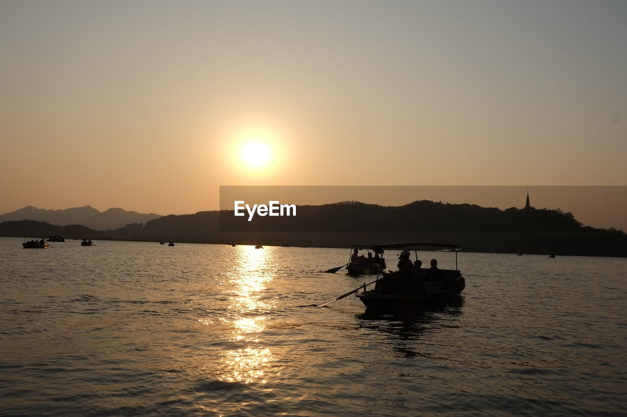 BOATS SAILING IN SEA AGAINST SKY DURING SUNSET