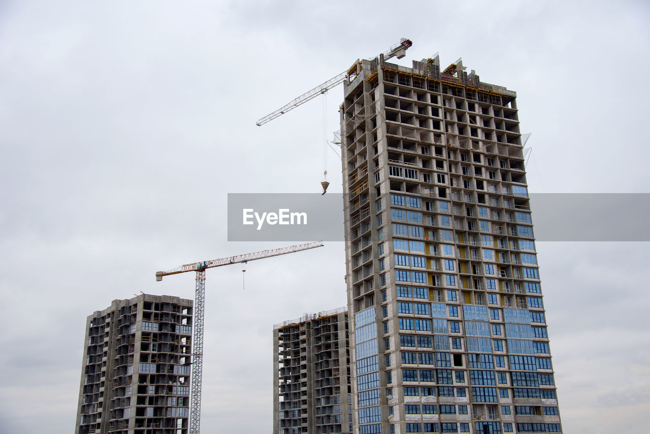 Tower cranes working at construction site against blue sky. crane lifting a concrete bucket. 