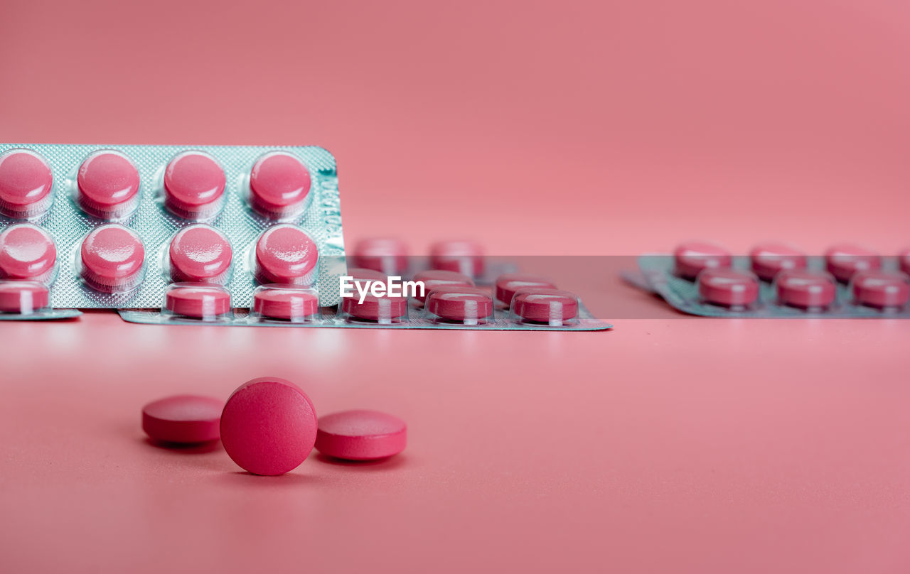 Pink tablet pills and blister pack of pills on pink background. prescription drug. vitamins, mineral