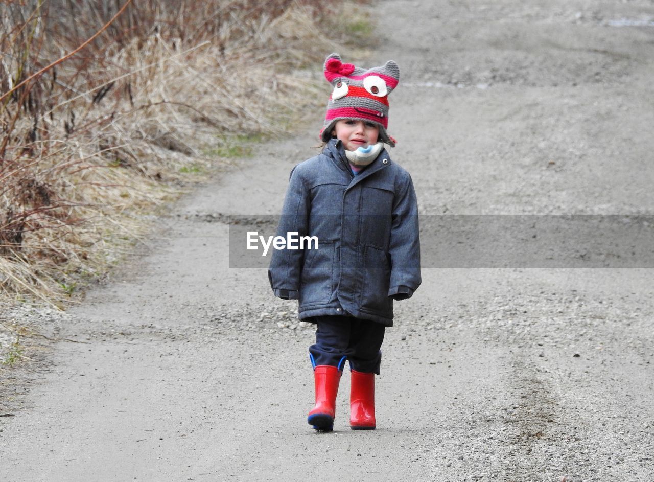 Portrait of smiling girl crying while standing on road during winter