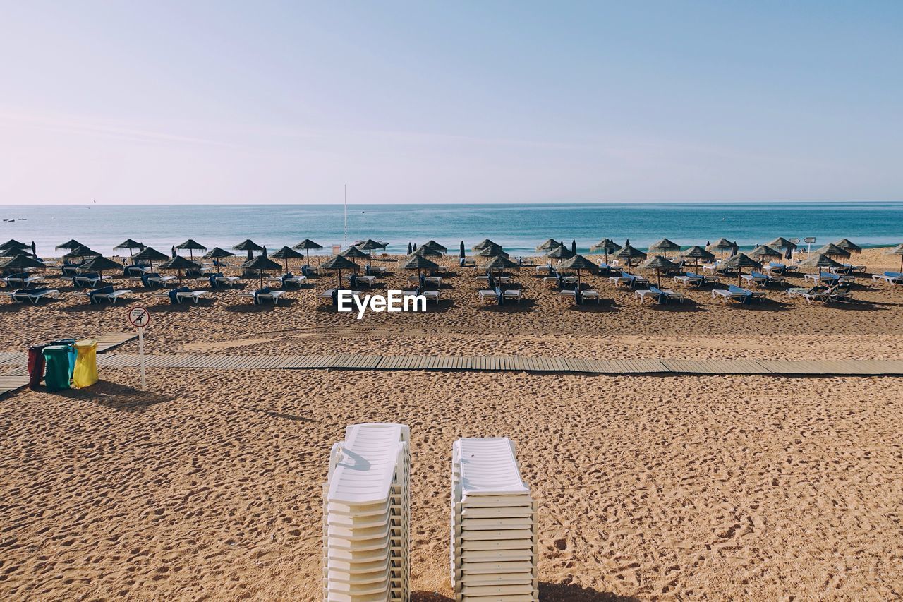 Parasols on shore at beach against sky