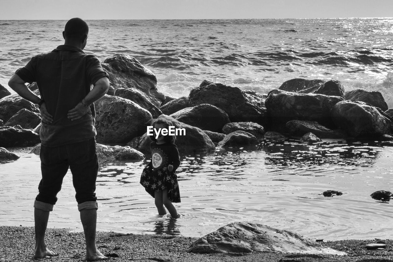 Full length of father standing by daughter at beach