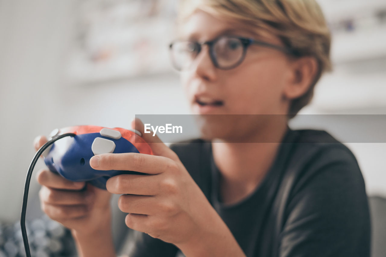 Close-up of cute boy playing video game at home