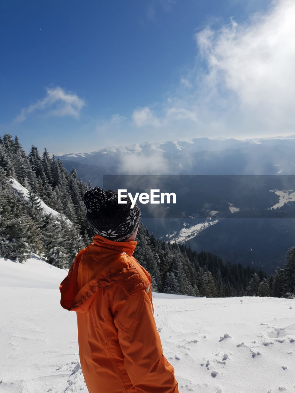 Rear view of person standing on snowcapped mountain against sky