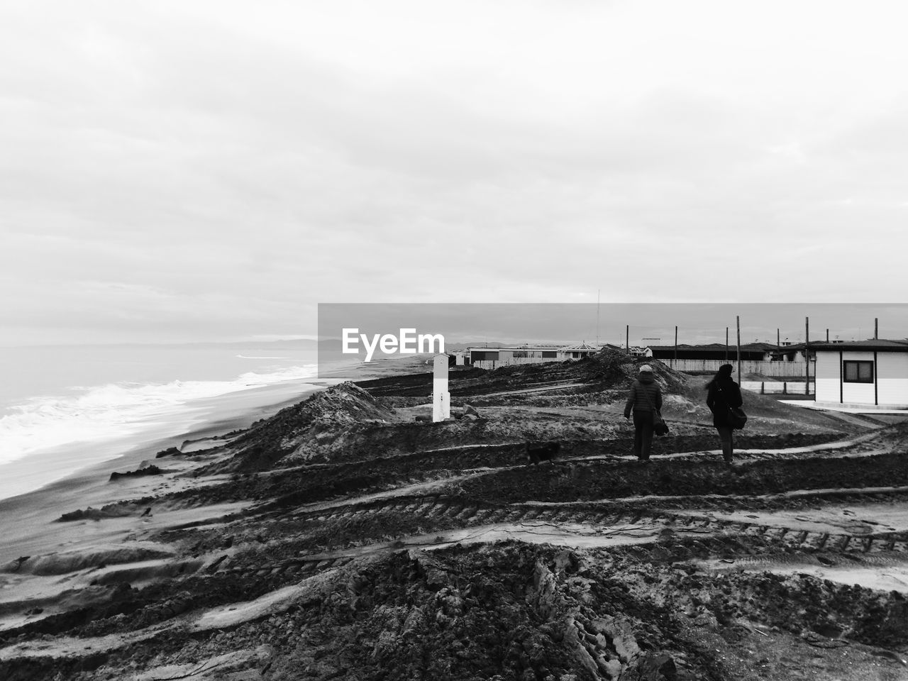 MEN STANDING ON BEACH AGAINST SKY