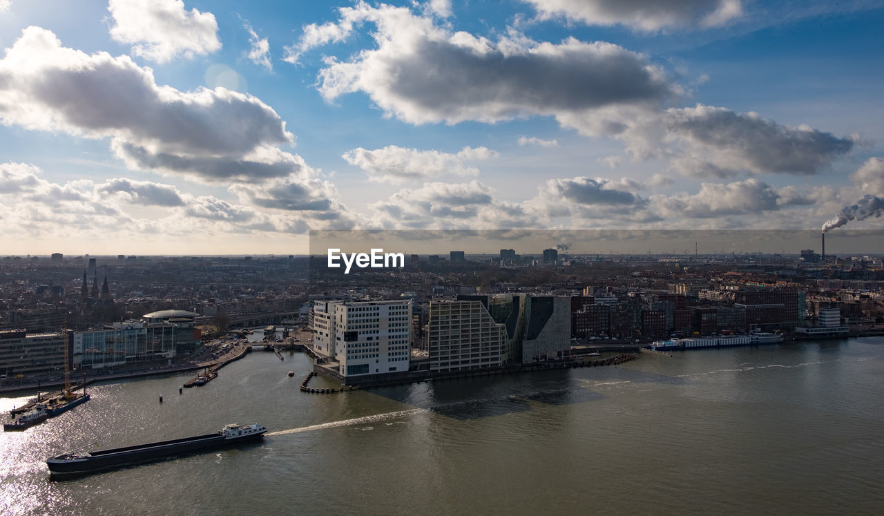 Scenic view of river by buildings against sky