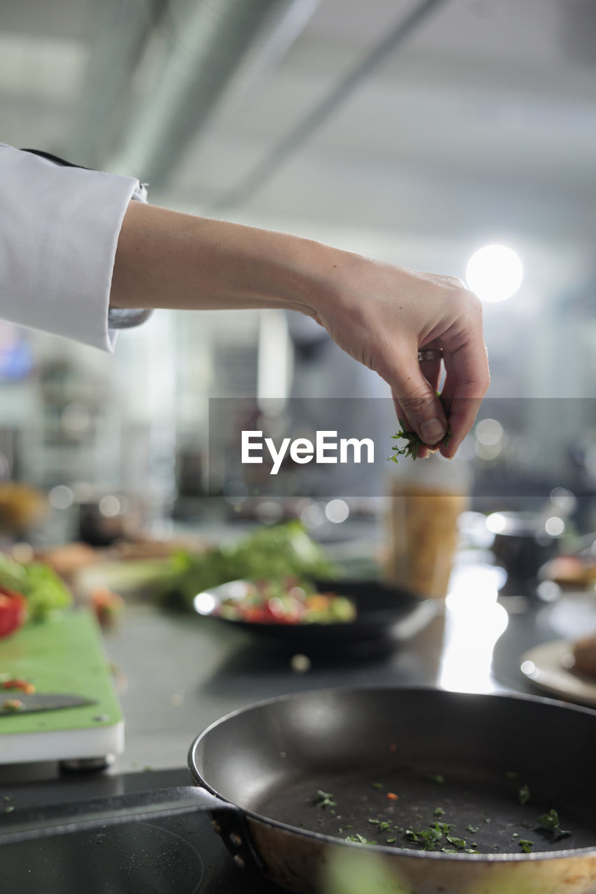 Cropped hand of chef preparing food