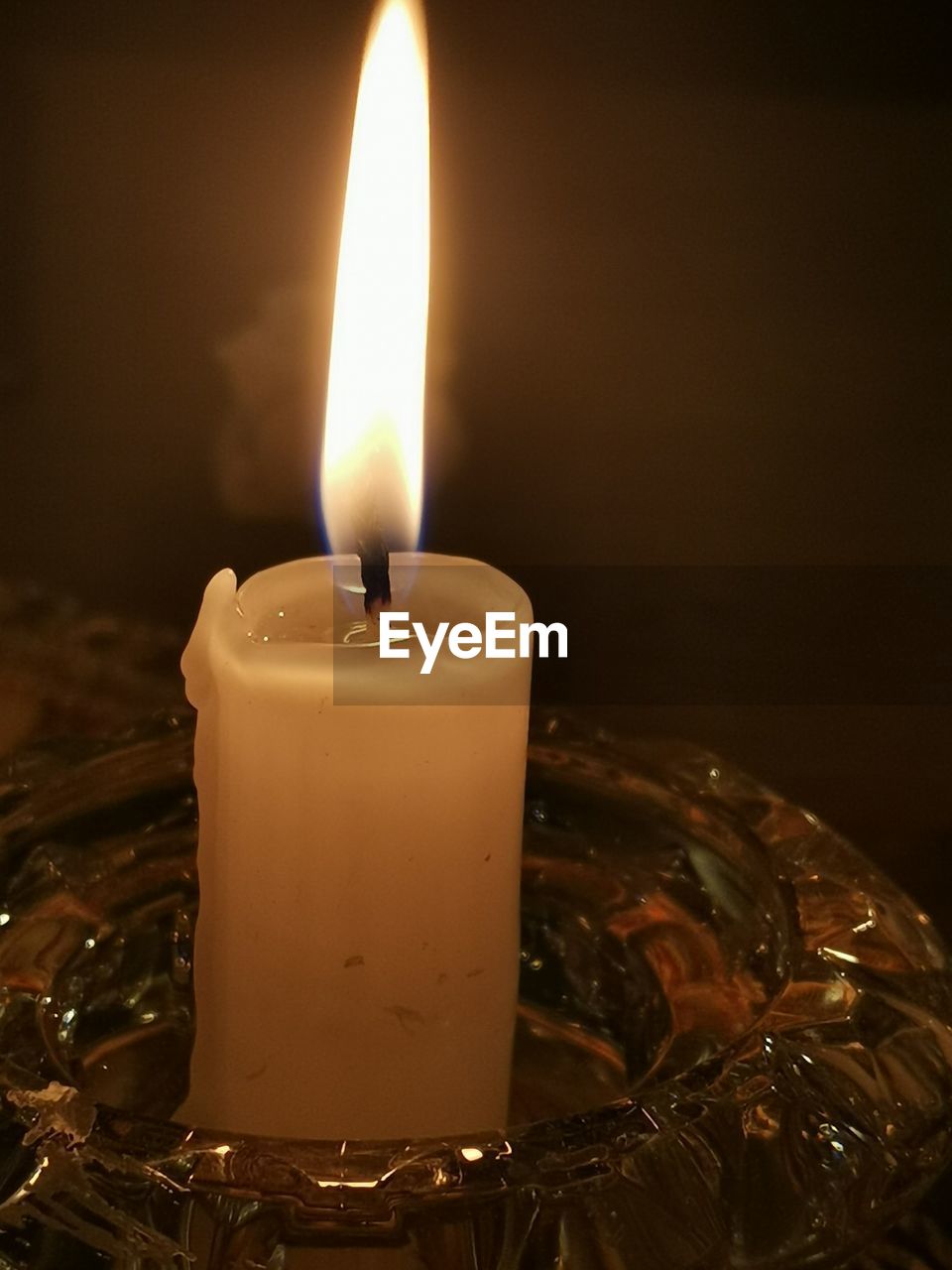 CLOSE-UP OF LIT CANDLE IN DARK