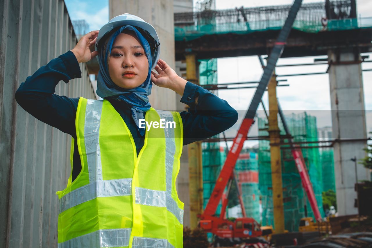 Portrait of young woman standing at construction site